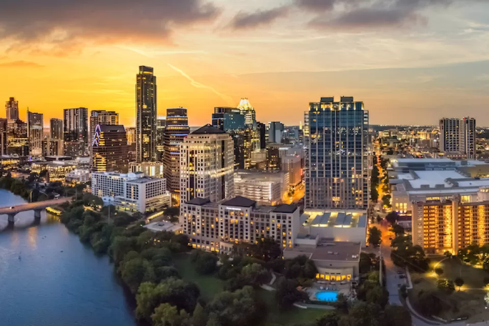 Austin, Texas skyline with river in foreground at sunset.